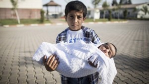 طفل رضيع مولود في تركيا يحمله أخاه الأكبر (أ ف ب)