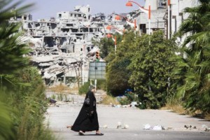 امرأة سورية تعبر قرب أحد المناطق التي دمرتها الحرب في سوريا/ راديو روزنة
