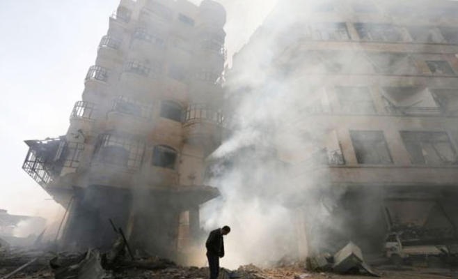 سوريٌّ يقف وسط منطقةٍ تعرّضت للقصف/ أرشيف