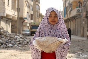 فتاة في حي الصالحين الفقير في حلب تحمل الخبز الذي يقوم بتوزيعه برنامج الأغذية العالمي/ WFP