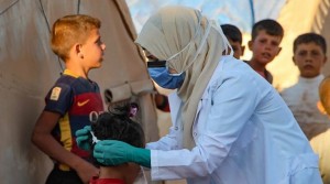 طبيبة سورية ترشد الأطفال على كيفية ارتداء قناع الوجه في ظلّ جائحة كورونا/ أ ف ب