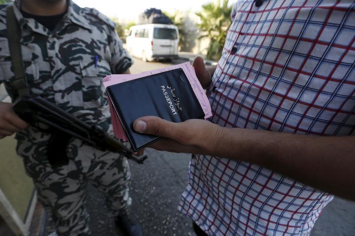 عنصر من الأمن العام يقف قرب سائق حافلة يحمل جوازات وبطاقات مغادرة لسوريين وافدين على لبنان. © 2015 رويترز