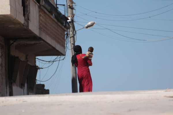 امرأة سوريّة من إدلب تحمل طفلها/ IWPR