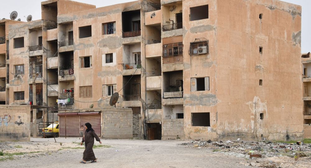 امراة سورية تسير بجوار بناءٍ تعرّض للقصف/ 2017