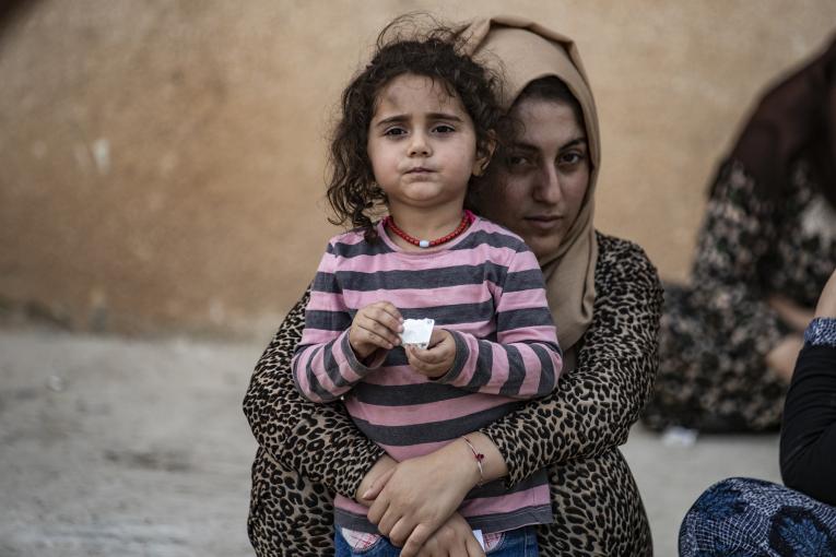 تحمل امرأة طفلة بينما تصل الأسر النازحة من رأس العين إلى تل تمر، بعد أن فرّت من العنف المتصاعد/ المصدر: يونيسيف