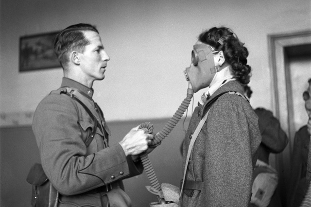 في هذه الصورة التي التقطت يوم 26 نوفمبر 1939، يشرح كبير الأطباء في الصليب الأحمر دينزلر لإحدى المتطوعات في منظمة الخدمة العسكرية للمرأة السويسرية كيفية ارتداء قناع غاز وضبطه. وقد تم الاعتراف بالمنظمة رسميًا في أبريل 1940.