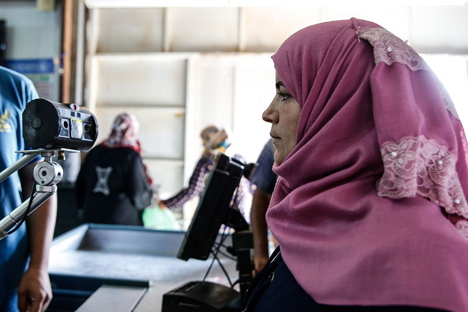 تقوم مستفيدة من هيئة الأمم المتحدة للمرأة بفحص عينيها، مما يسمح لها بشراء الحاجيات من سوبر ماركت في مخيم الأزرق للاجئين، الأردن. الصورة: هيئة الأمم المتحدة للمرأة/لورين روني